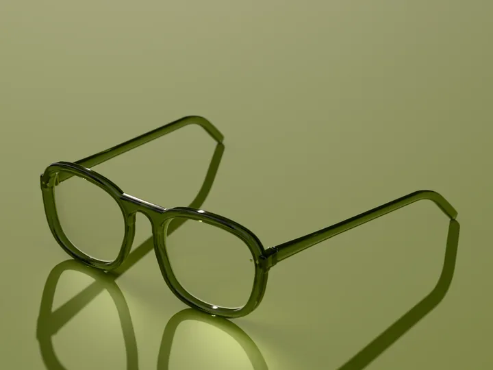 Ivo square glasses in Olive crystal, in low sun on a warm ground