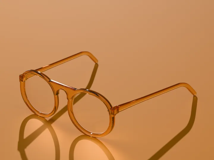 Mira round glasses in Honey amber, in low sun on a warm ground
